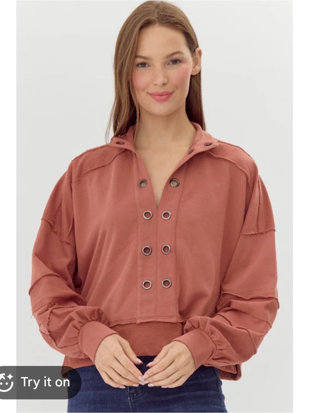This Pilcro Anthropologie grommet sweatshirt features a coral pink color and raw